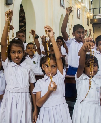 Children in uniforms holding up rosaries