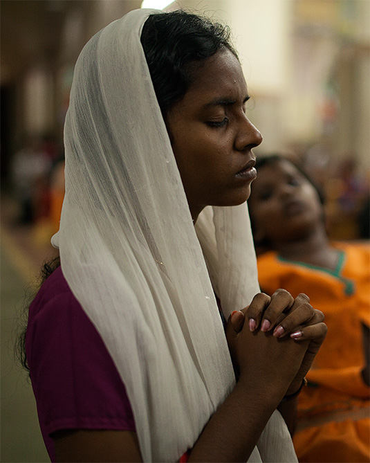 Young woman praying with eyes closed