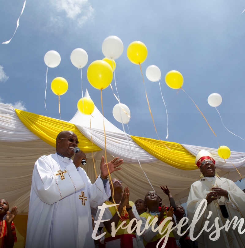Priests smiling, celebrating with balloons and group behind them